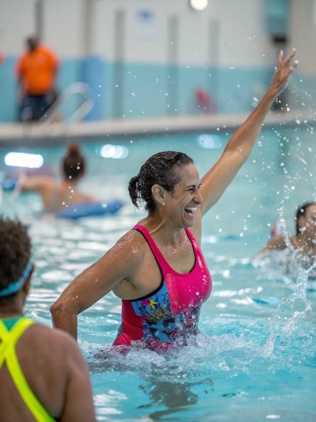 A diverse group of adults participating in a water aerobics class at PISCINE INTERCOMMUNALE VALLEE DE L'OZE, led by an instructor, showcasing the fun and fitness benefits.